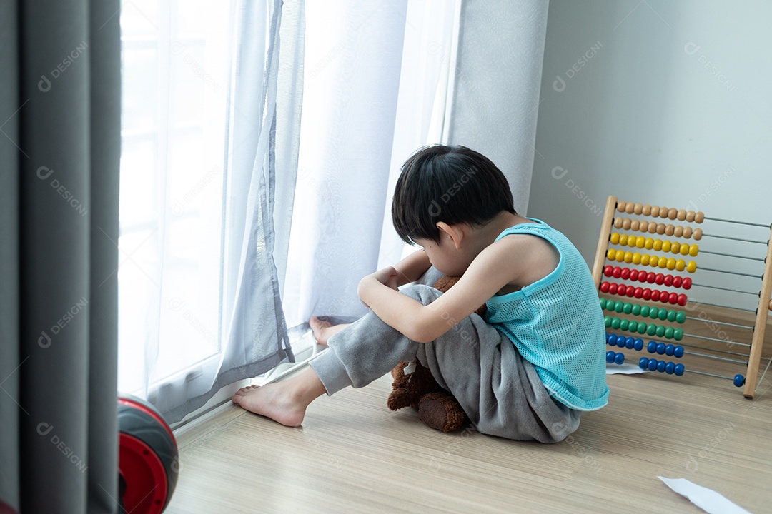 Triste menino asiático senta-se com a cabeça baixa