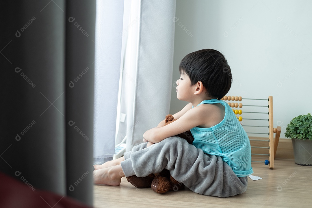 Triste menino asiático senta-se com a cabeça baixa