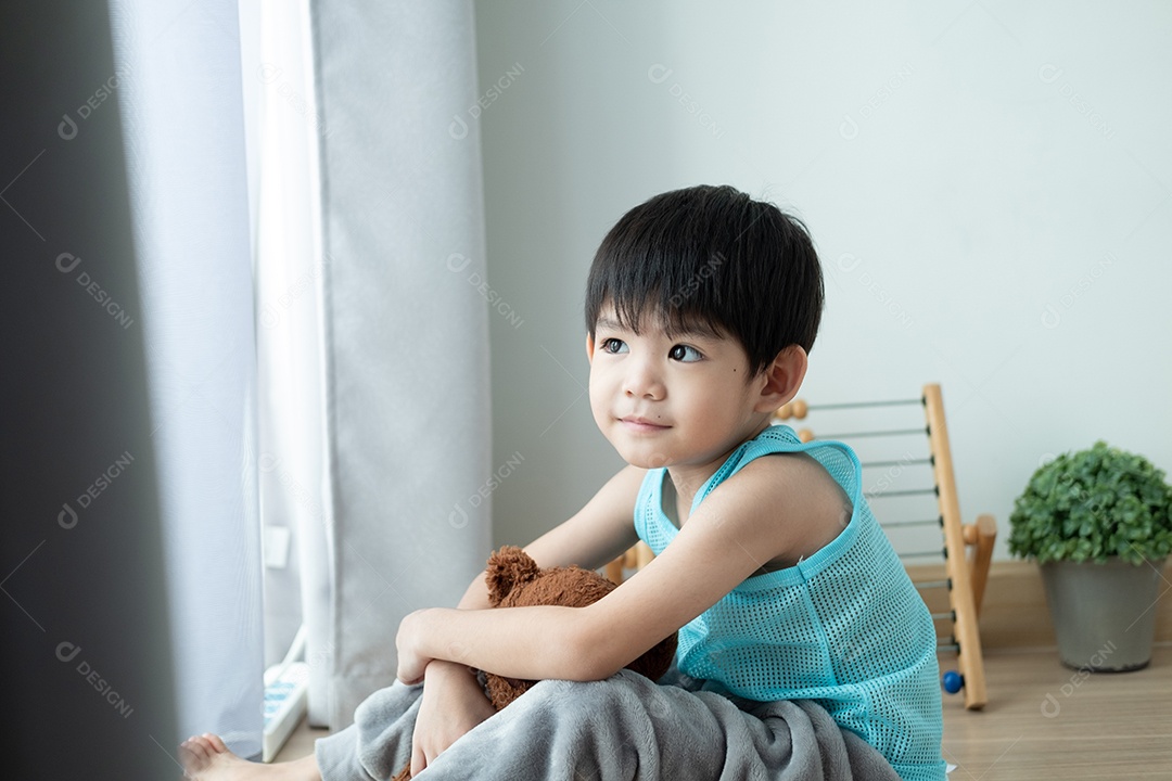 Triste menino asiático senta-se com a cabeça baixa