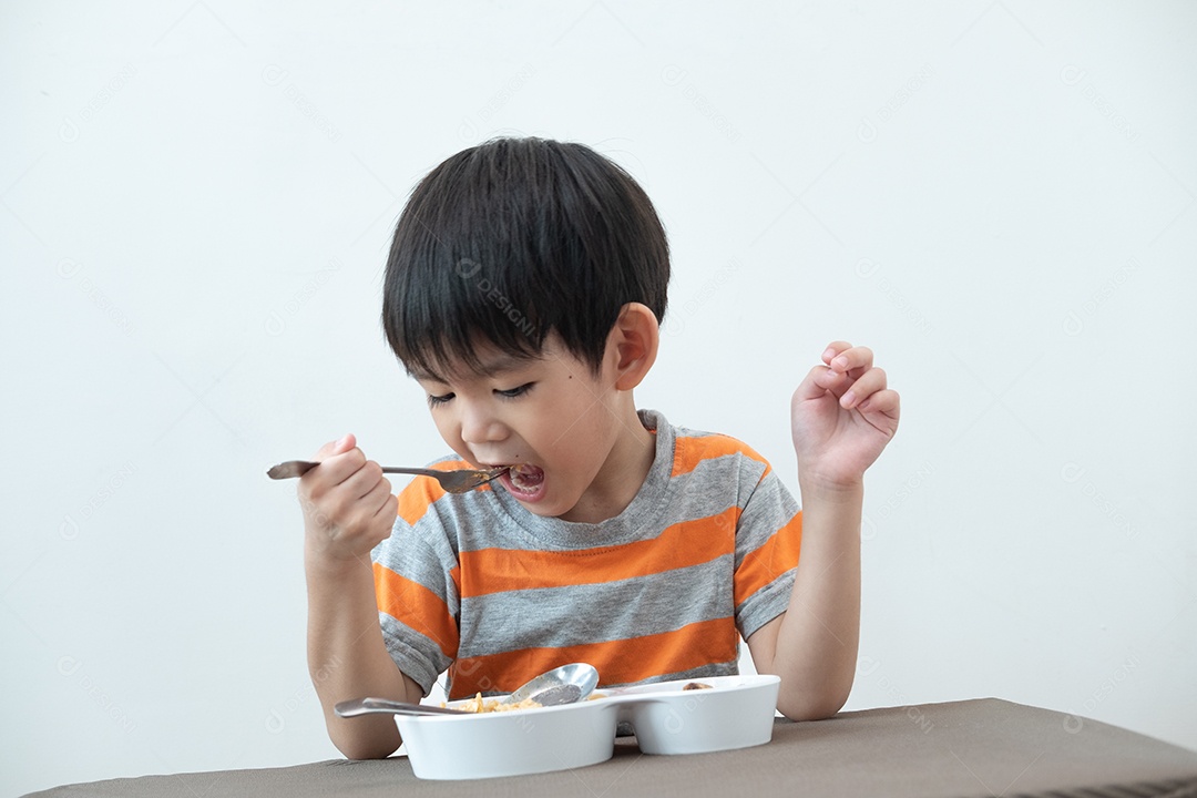 Menino asiático comendo macarrão em cima da mesa