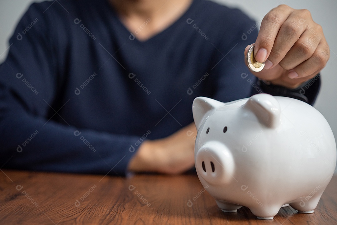 Homem segurando um cofrinho de moedas.investimento financeiro e bancário, poupança de dinheiro