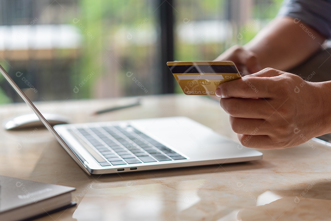 mãos de homem segurando cartão de crédito usando computador portátil de pagamento pela internet, banco digital de compras on-line