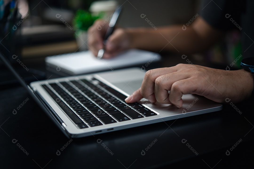 Homem digitando no teclado do computador portátil, procurando informações ou fazendo trabalho freelance.