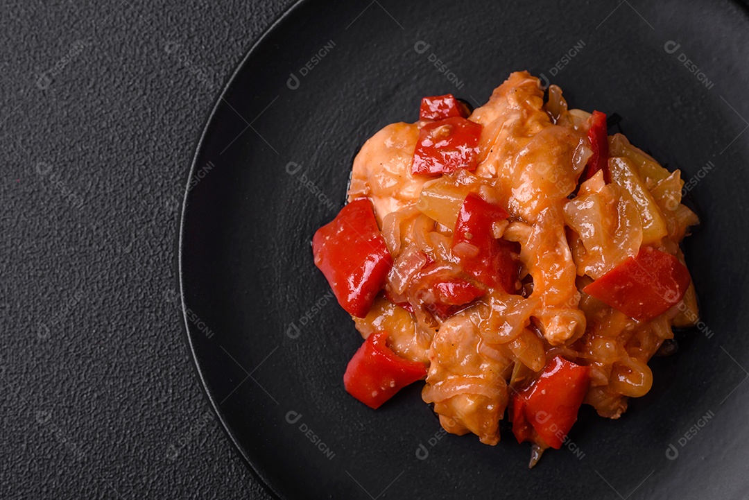 Deliciosa salada fresca com fatias de frango grelhado, abacaxi, pimentão, nozes e molho em um prato de cerâmica sobre um fundo escuro de concreto