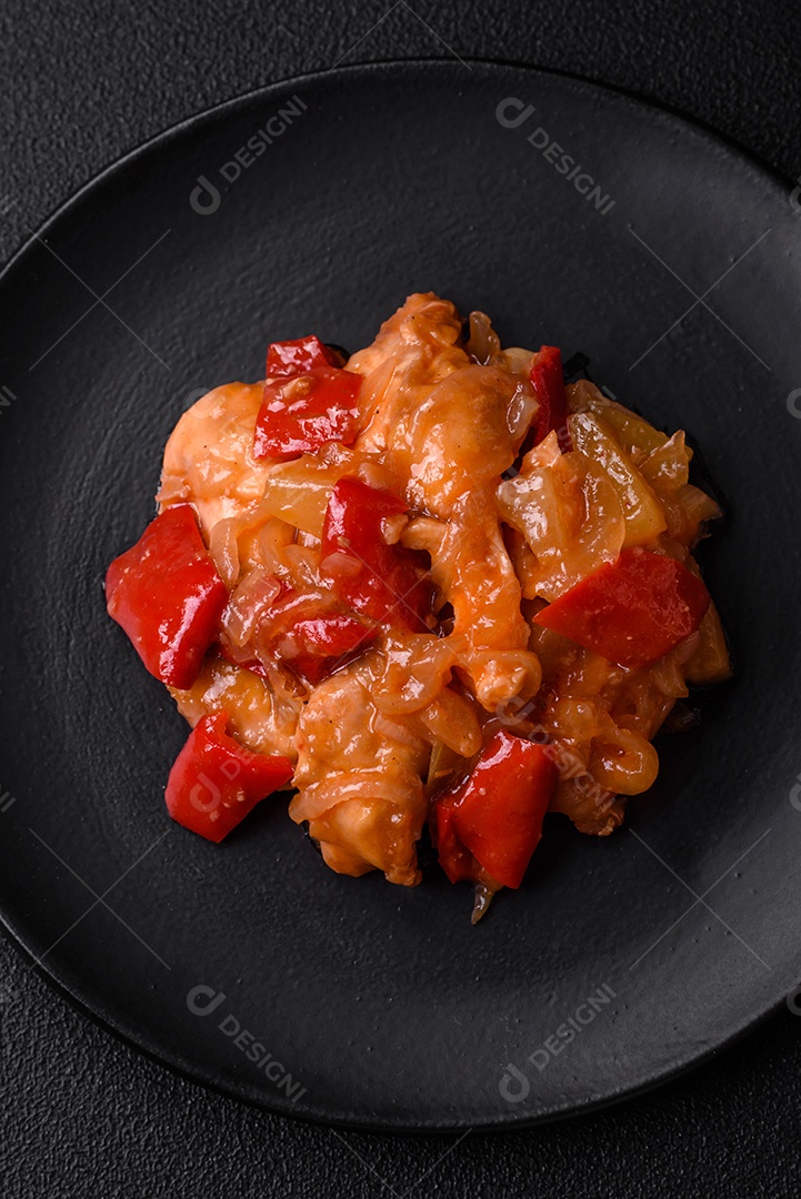 Deliciosa salada fresca com fatias de frango grelhado, abacaxi, pimentão, nozes e molho em um prato de cerâmica sobre um fundo escuro de concreto