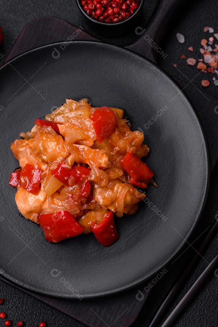 Deliciosa salada fresca com fatias de frango grelhado, abacaxi, pimentão, nozes e molho em um prato de cerâmica sobre um fundo escuro de concreto