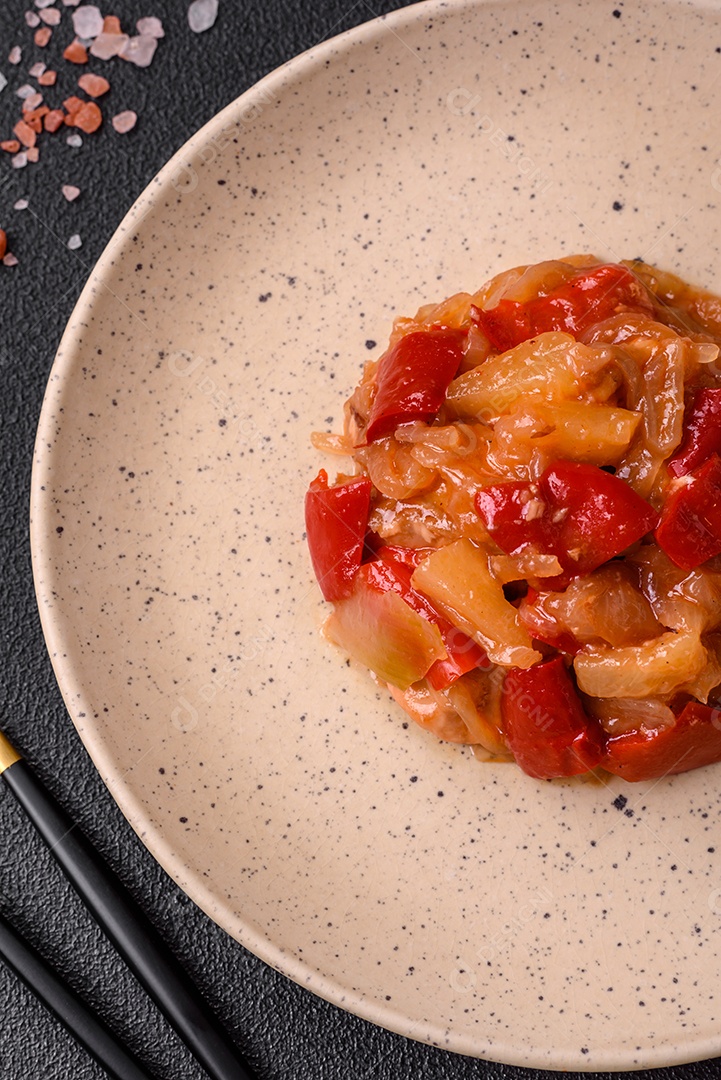 Deliciosa salada fresca com fatias de frango grelhado, abacaxi, pimentão, nozes e molho em um prato de cerâmica sobre um fundo escuro de concreto