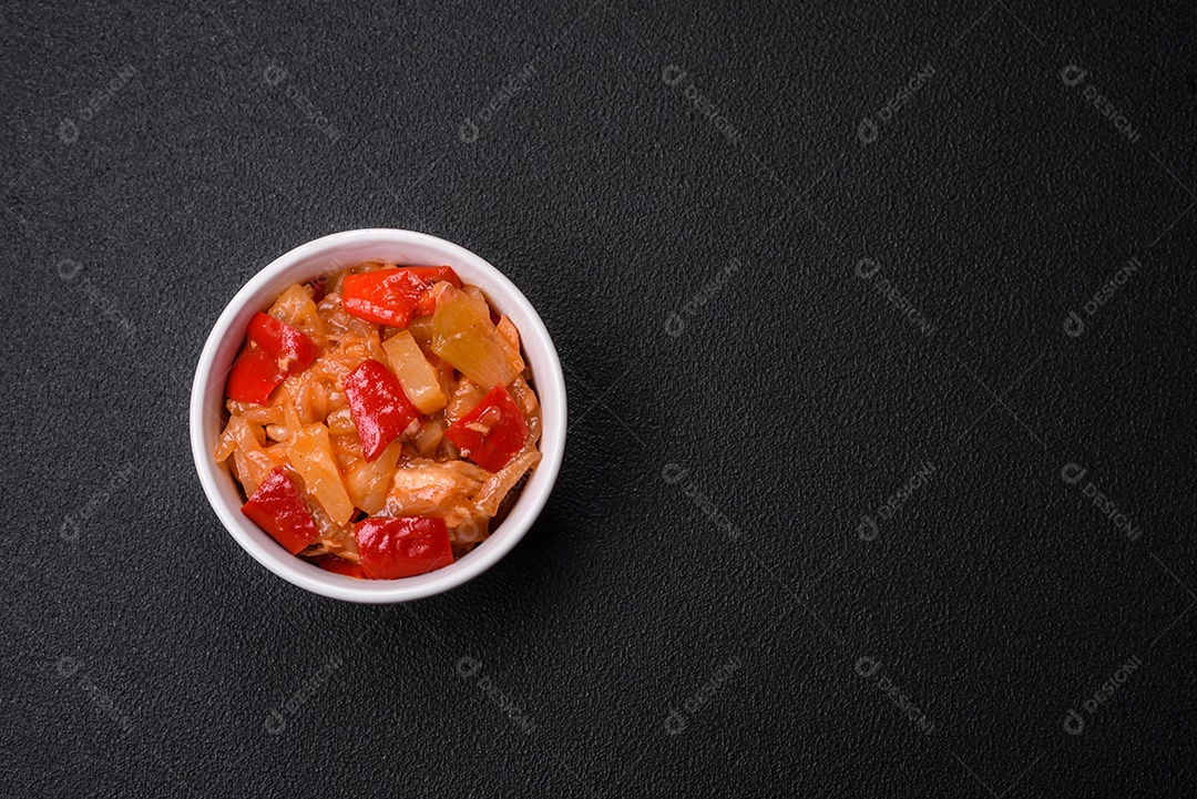 Deliciosa salada fresca com fatias de frango grelhado, abacaxi, pimentão, nozes e molho em um prato de cerâmica sobre um fundo escuro de concreto