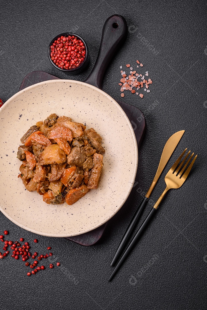 Salada quente com vitela, tomate, pimentão, abobrinha, gergelim, sal, especiarias e ervas sobre fundo escuro de concreto