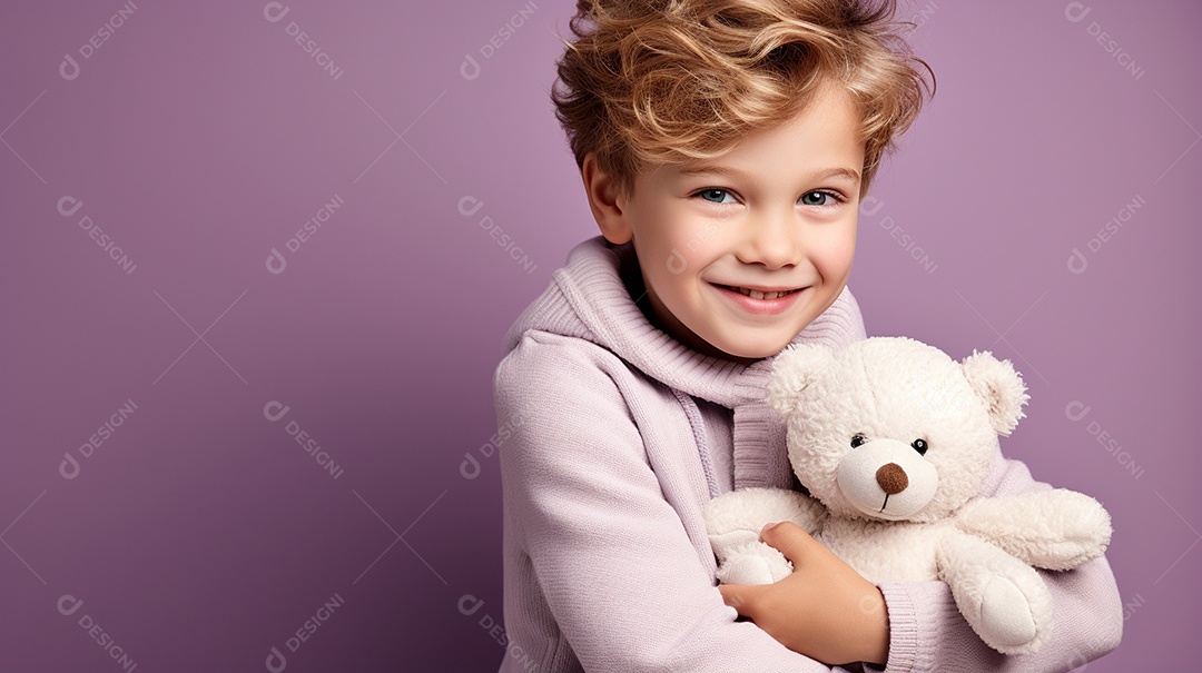 Garoto branco em roupas casuais se diverte, abraça o ursinho de pelúcia