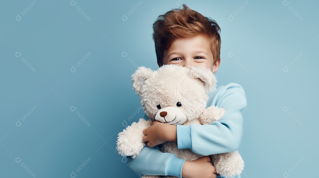 Garoto branco em roupas casuais se diverte, abraça o ursinho de pelúcia