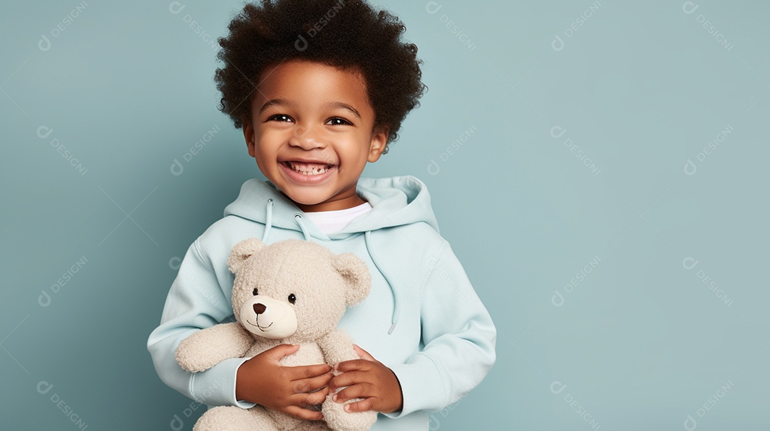 Garoto negro com roupas casuais se diverte, abraça o ursinho de pelúcia