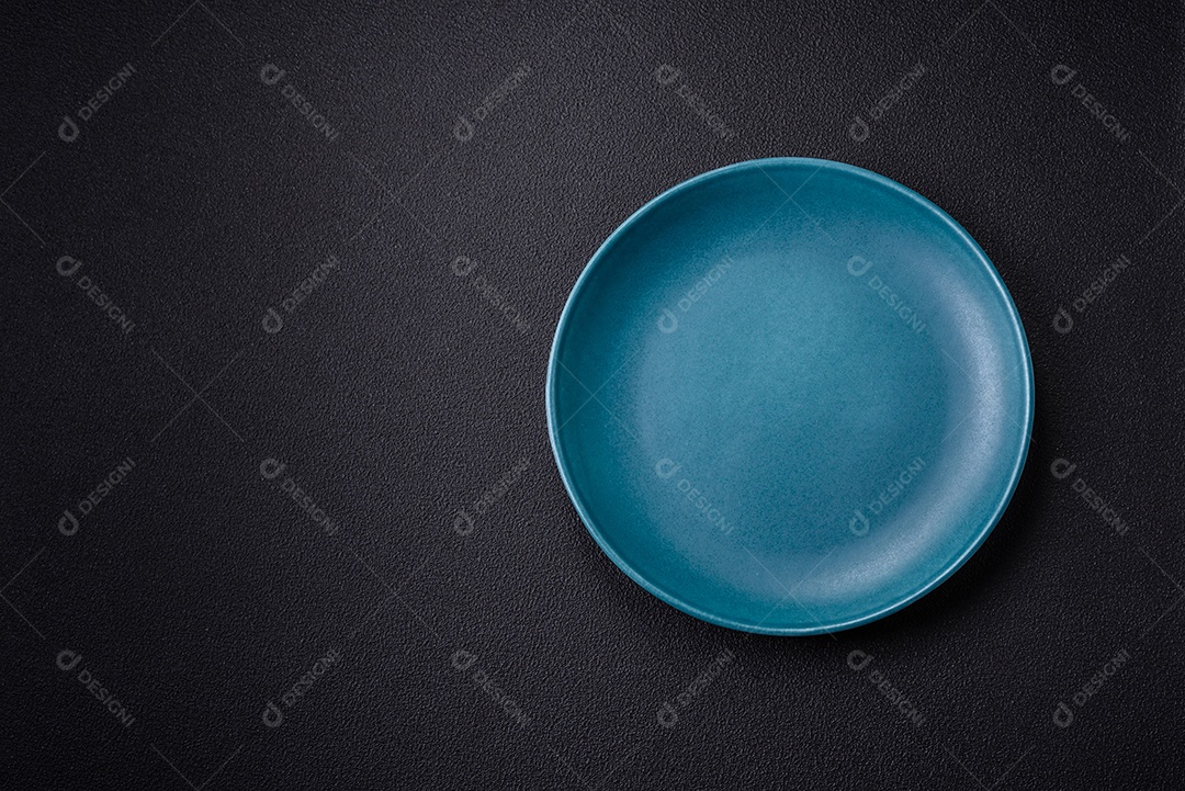 Linda placa cerâmica redonda vazia sobre um fundo de concreto. Utensílios de cozinha para servir comida na mesa