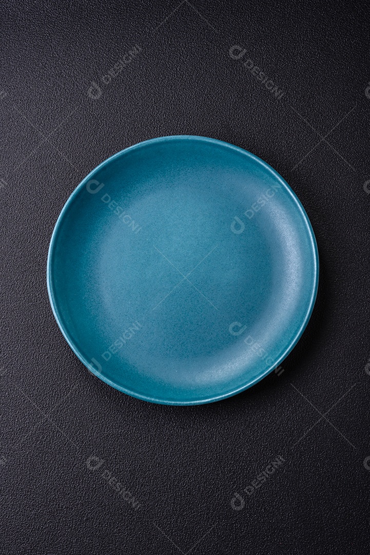 Linda placa cerâmica redonda vazia sobre um fundo de concreto. Utensílios de cozinha para servir comida na mesa