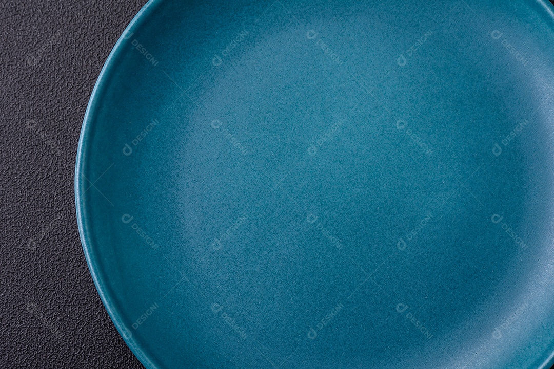 Linda placa cerâmica redonda vazia sobre um fundo de concreto. Utensílios de cozinha para servir comida na mesa