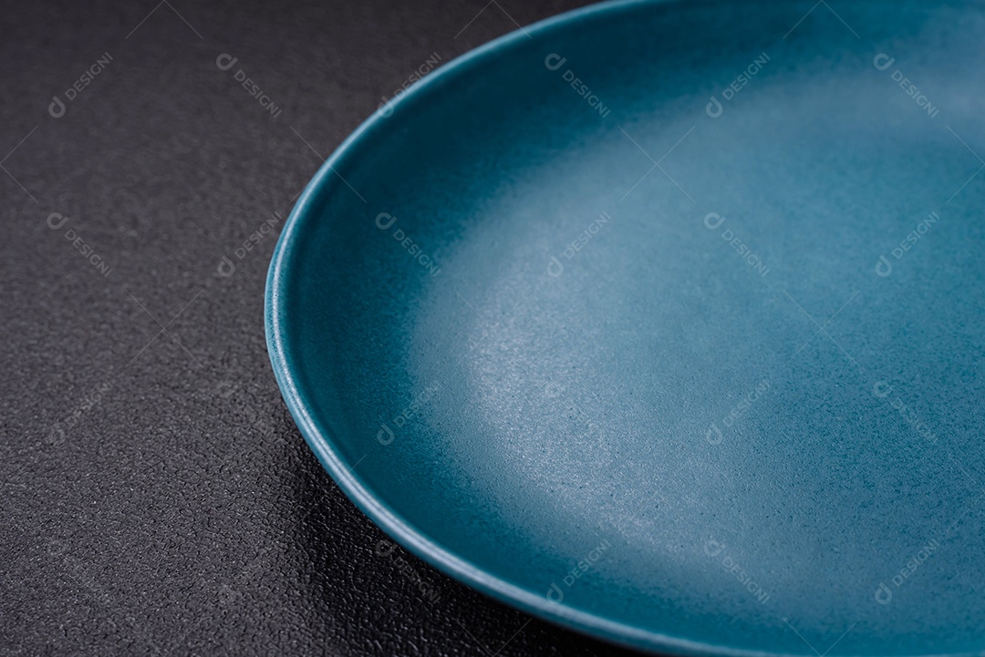 Linda placa cerâmica redonda vazia sobre um fundo de concreto. Utensílios de cozinha para servir comida na mesa