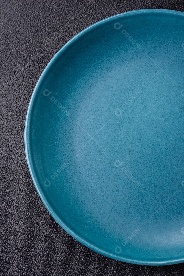 Linda placa cerâmica redonda vazia sobre um fundo de concreto. Utensílios de cozinha para servir comida na mesa