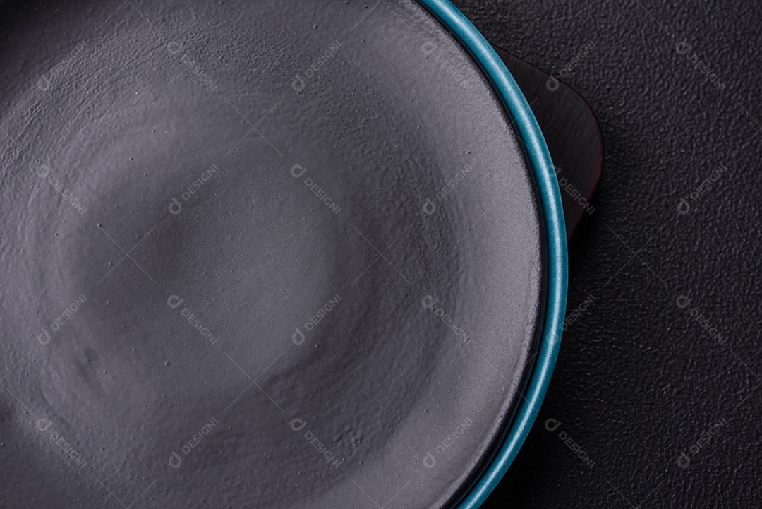 Linda placa cerâmica redonda vazia sobre um fundo de concreto. Utensílios de cozinha para servir comida na mesa