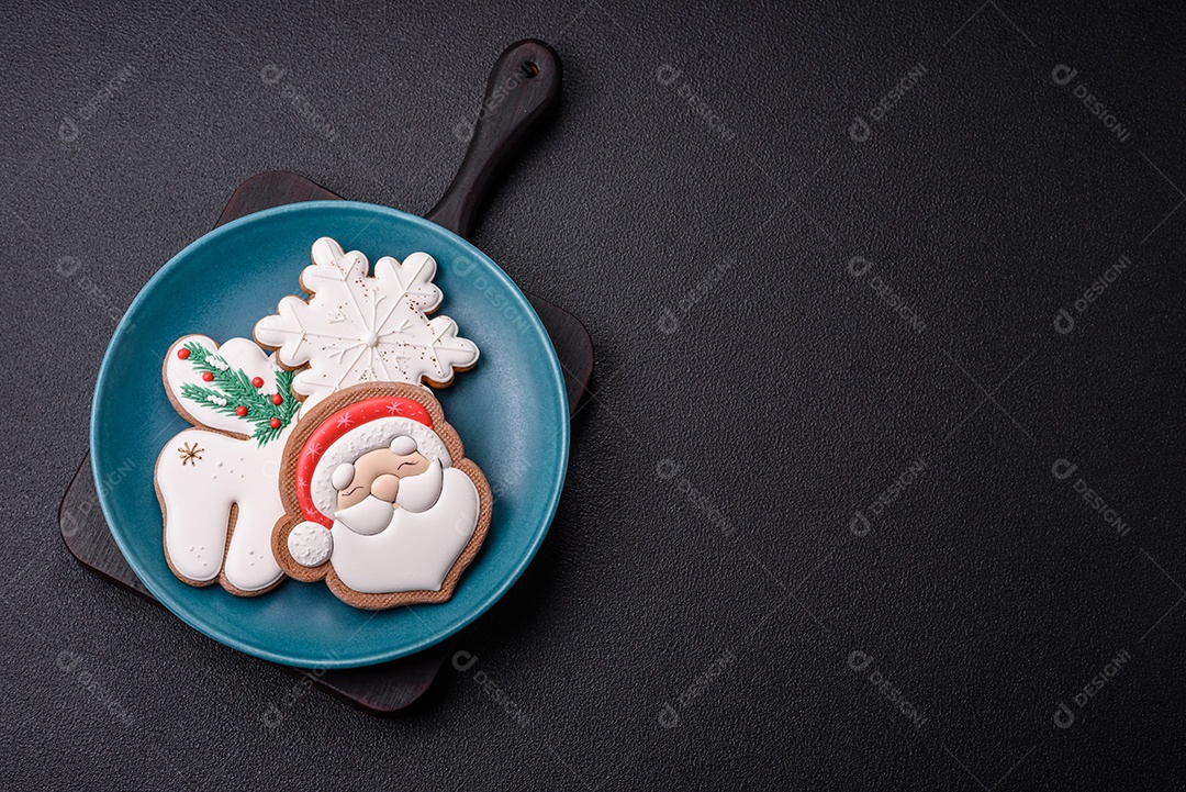 Lindos biscoitos de gengibre de Natal em uma placa cerâmica redonda sobre um fundo de concreto texturizado