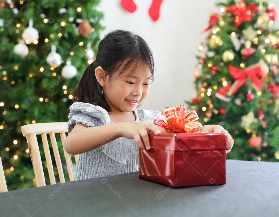 Criança asiática feliz desembrulhando um presente no natal