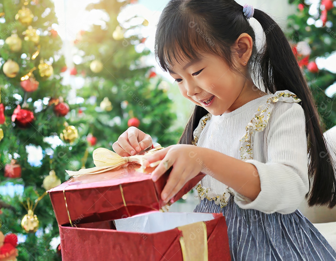 Criança asiática feliz desembrulhando um presente no natal