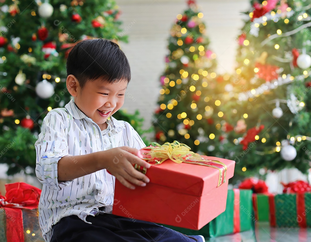 Criança asiática feliz desembrulhando um presente no natal
