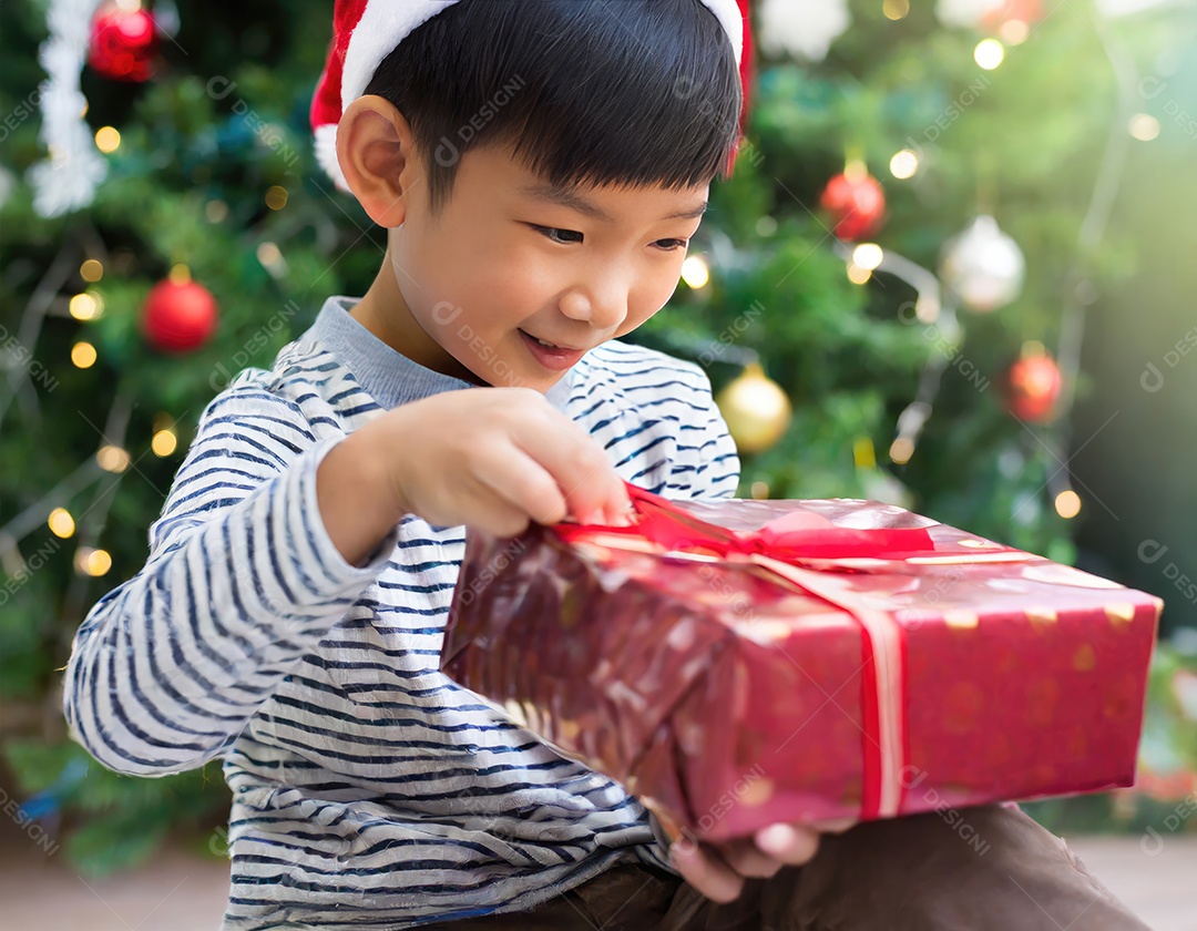 Criança asiática feliz desembrulhando um presente no natal