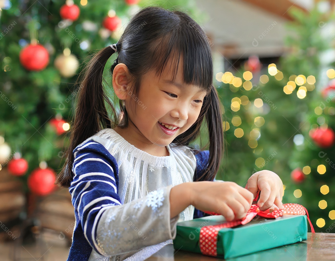 Criança asiática feliz desembrulhando um presente no natal