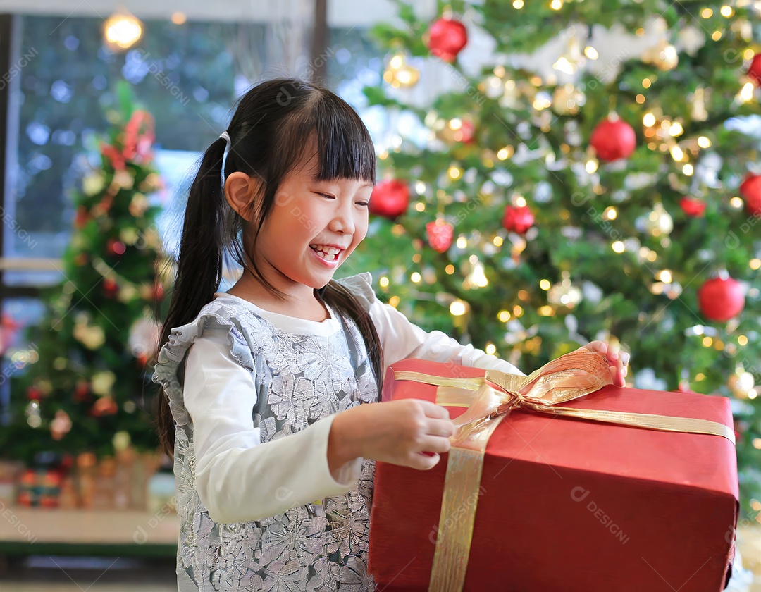 Criança asiática feliz desembrulhando um presente no natal