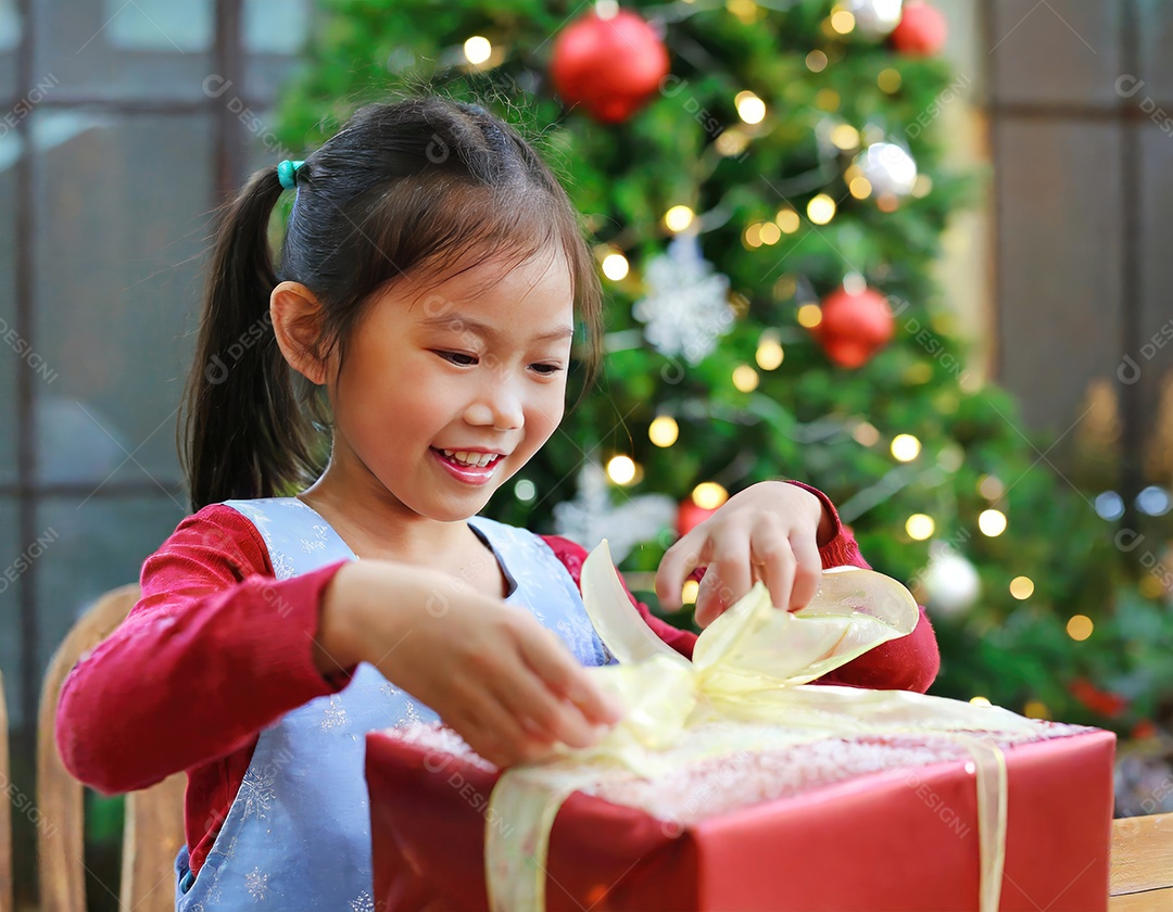 Criança asiática feliz desembrulhando um presente no natal