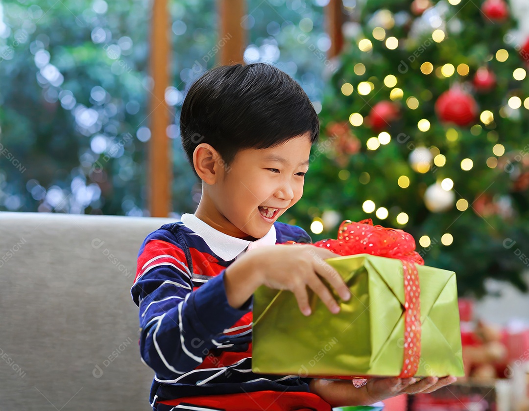 Criança asiática feliz desembrulhando um presente no natal