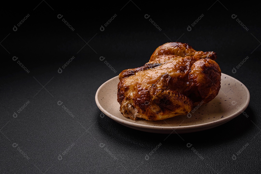 Frango assado inteiro delicioso e crocante com legumes, sal e especiarias sobre um fundo escuro de concreto
