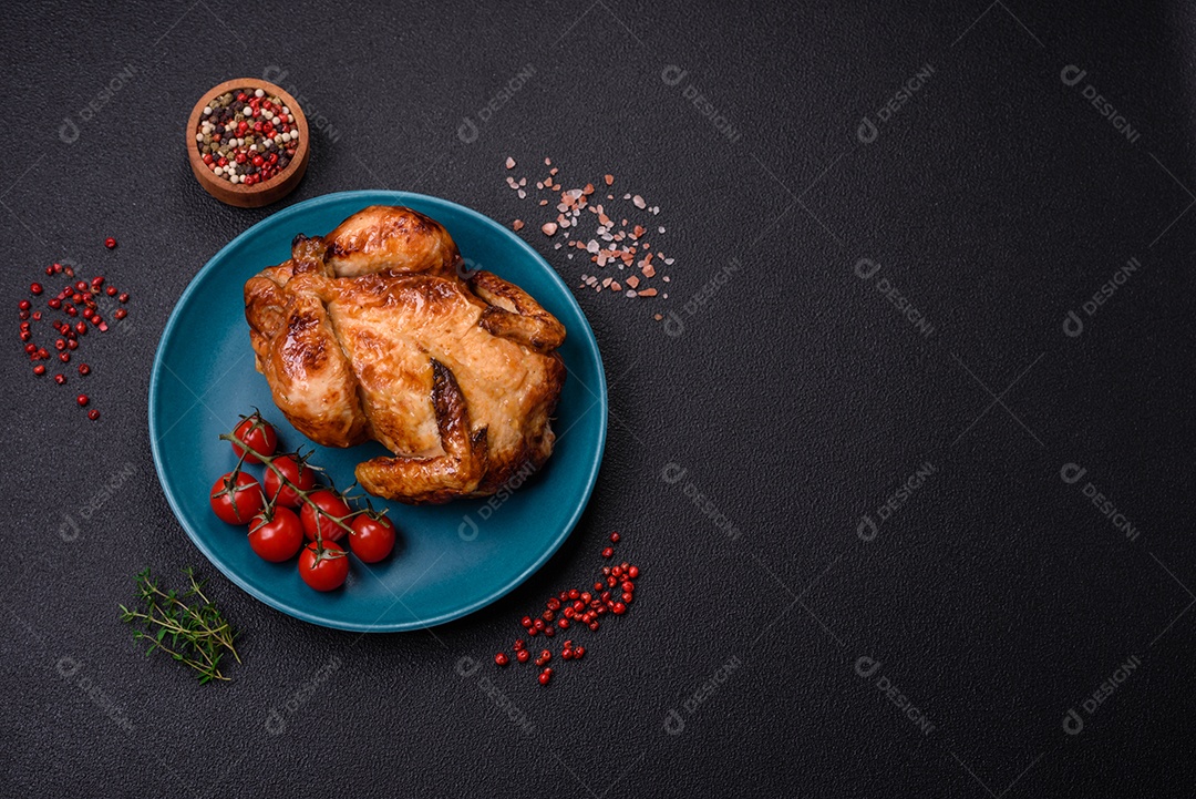 Frango assado inteiro delicioso e crocante com legumes, sal e especiarias sobre um fundo escuro de concreto