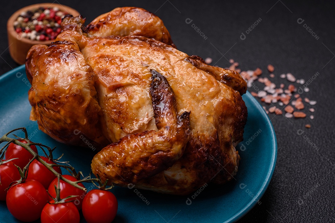 Frango assado inteiro delicioso e crocante com legumes, sal e especiarias sobre um fundo escuro de concreto