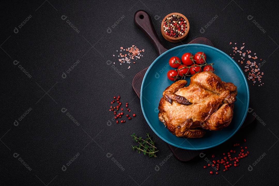 Frango assado inteiro delicioso e crocante com legumes, sal e especiarias sobre um fundo escuro de concreto