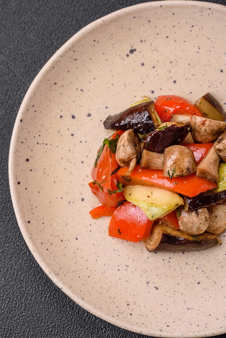 Deliciosa salada de legumes grelhados, tomates, cogumelos, pimentões, berinjelas, abobrinha, sal, especiarias e ervas em um prato cerâmico