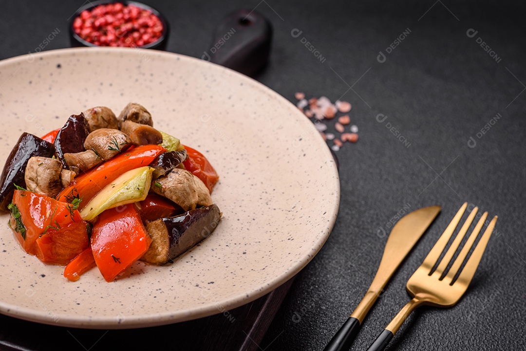 Deliciosa salada de legumes grelhados, tomates, cogumelos, pimentões, berinjelas, abobrinha, sal, especiarias e ervas em um prato cerâmico