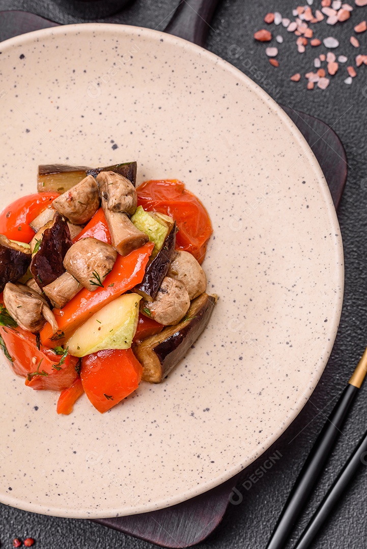 Deliciosa salada de legumes grelhados, tomates, cogumelos, pimentões, berinjelas, abobrinha, sal, especiarias e ervas em um prato cerâmico