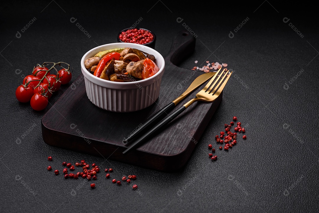 Deliciosa salada de legumes grelhados, tomates, cogumelos, pimentões, berinjelas, abobrinha, sal, especiarias e ervas em um prato cerâmico