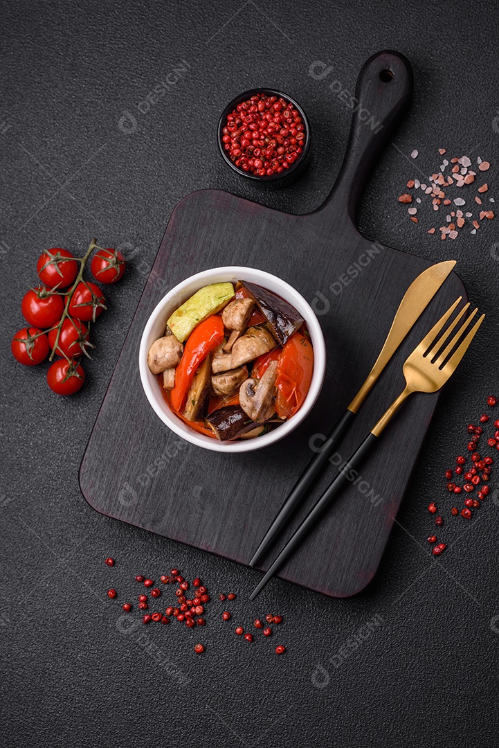 Deliciosa salada de legumes grelhados, tomates, cogumelos, pimentões, berinjelas, abobrinha, sal, especiarias e ervas em um prato cerâmico