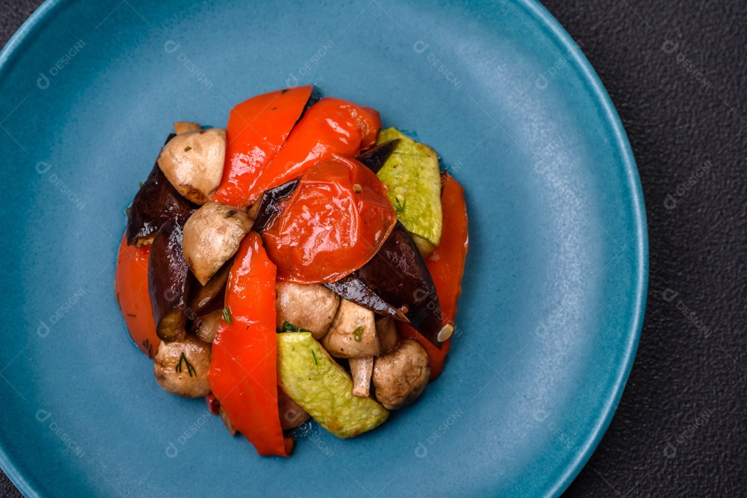 Deliciosa salada de legumes grelhados, tomates, cogumelos, pimentões, berinjelas, abobrinha, sal, especiarias e ervas em um prato cerâmico