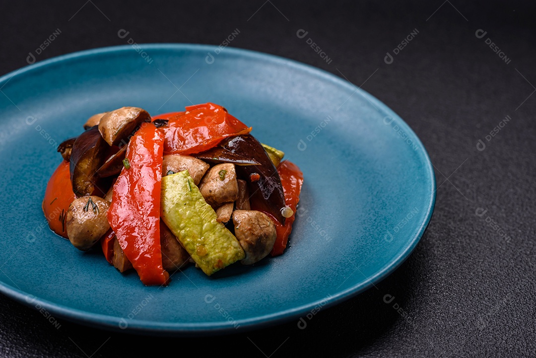 Deliciosa salada de legumes grelhados, tomates, cogumelos, pimentões, berinjelas, abobrinha, sal, especiarias e ervas em um prato cerâmico