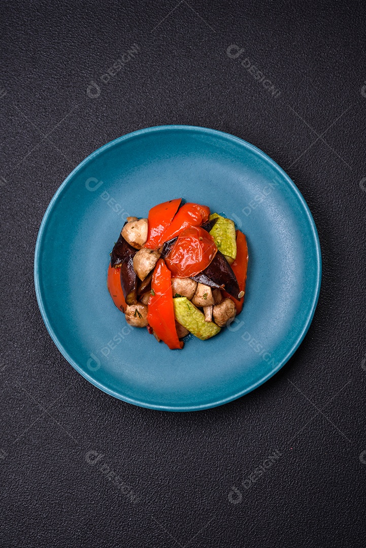 Deliciosa salada de legumes grelhados, tomates, cogumelos, pimentões, berinjelas, abobrinha, sal, especiarias e ervas em um prato cerâmico