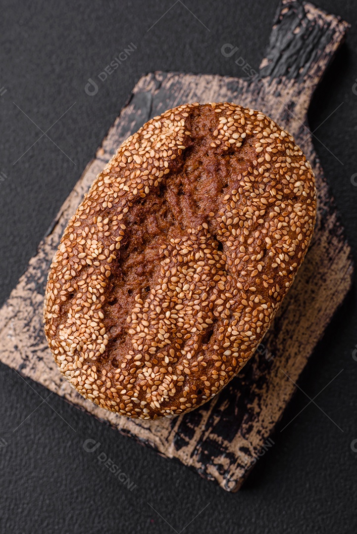 Delicioso pão integral crocante fresco com sementes e grãos sobre um fundo escuro de concreto