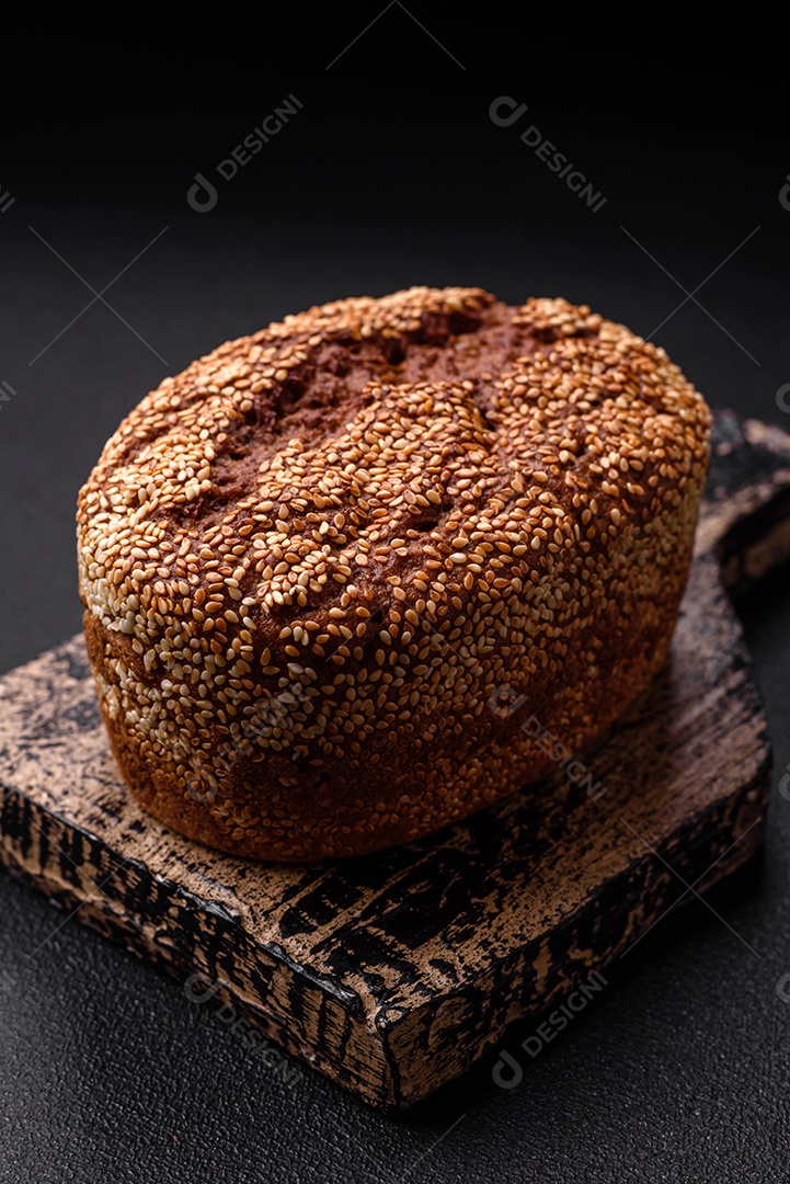 Delicioso pão integral crocante fresco com sementes e grãos sobre um fundo escuro de concreto