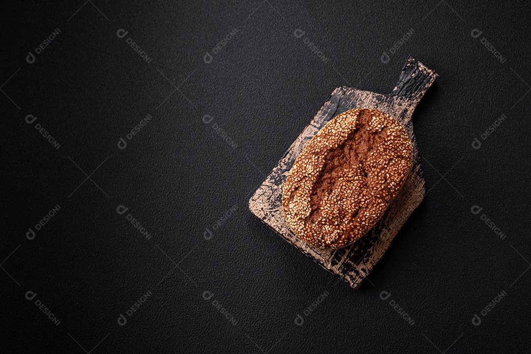 Delicioso pão integral crocante fresco com sementes e grãos sobre um fundo escuro de concreto