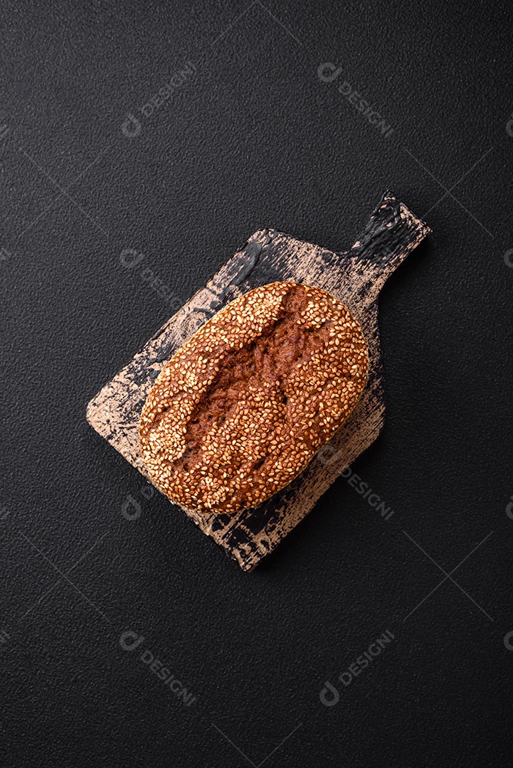 Delicioso pão integral crocante fresco com sementes e grãos sobre um fundo escuro de concreto