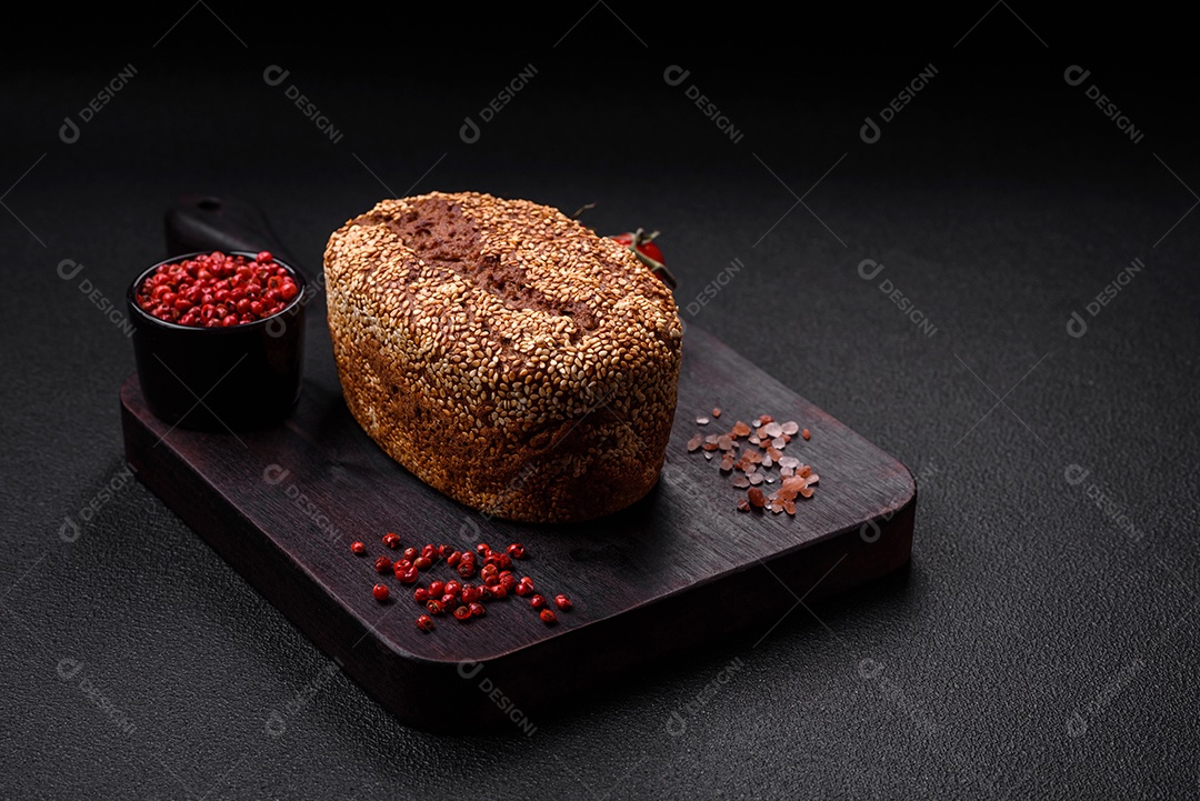 Delicioso pão integral crocante fresco com sementes e grãos sobre um fundo escuro de concreto