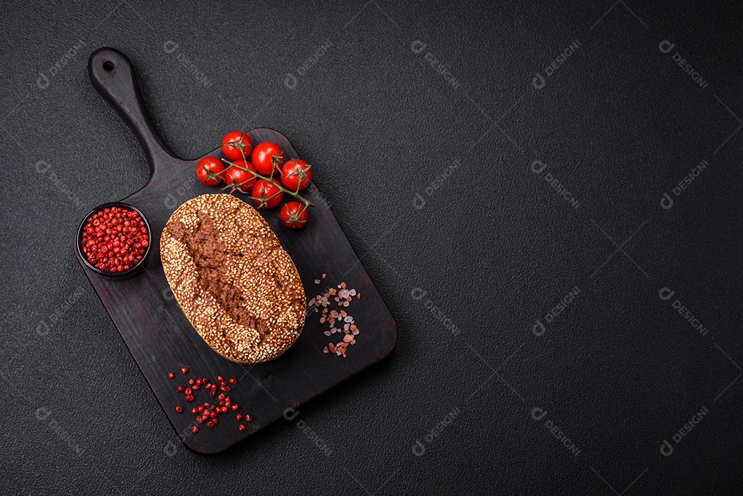 Delicioso pão integral crocante fresco com sementes e grãos sobre um fundo escuro de concreto