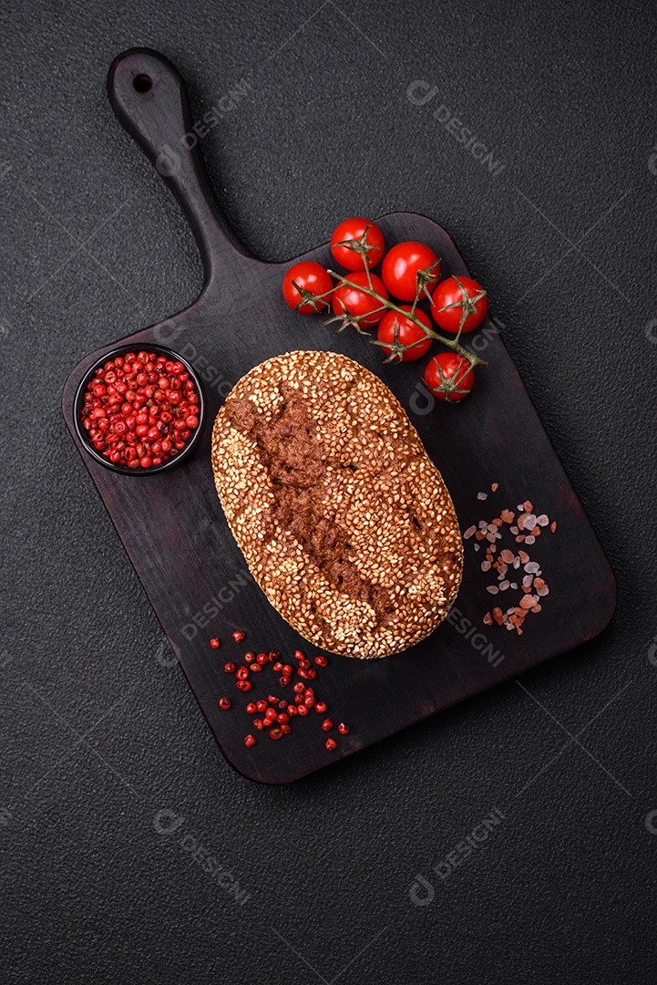 Delicioso pão integral crocante fresco com sementes e grãos sobre um fundo escuro de concreto